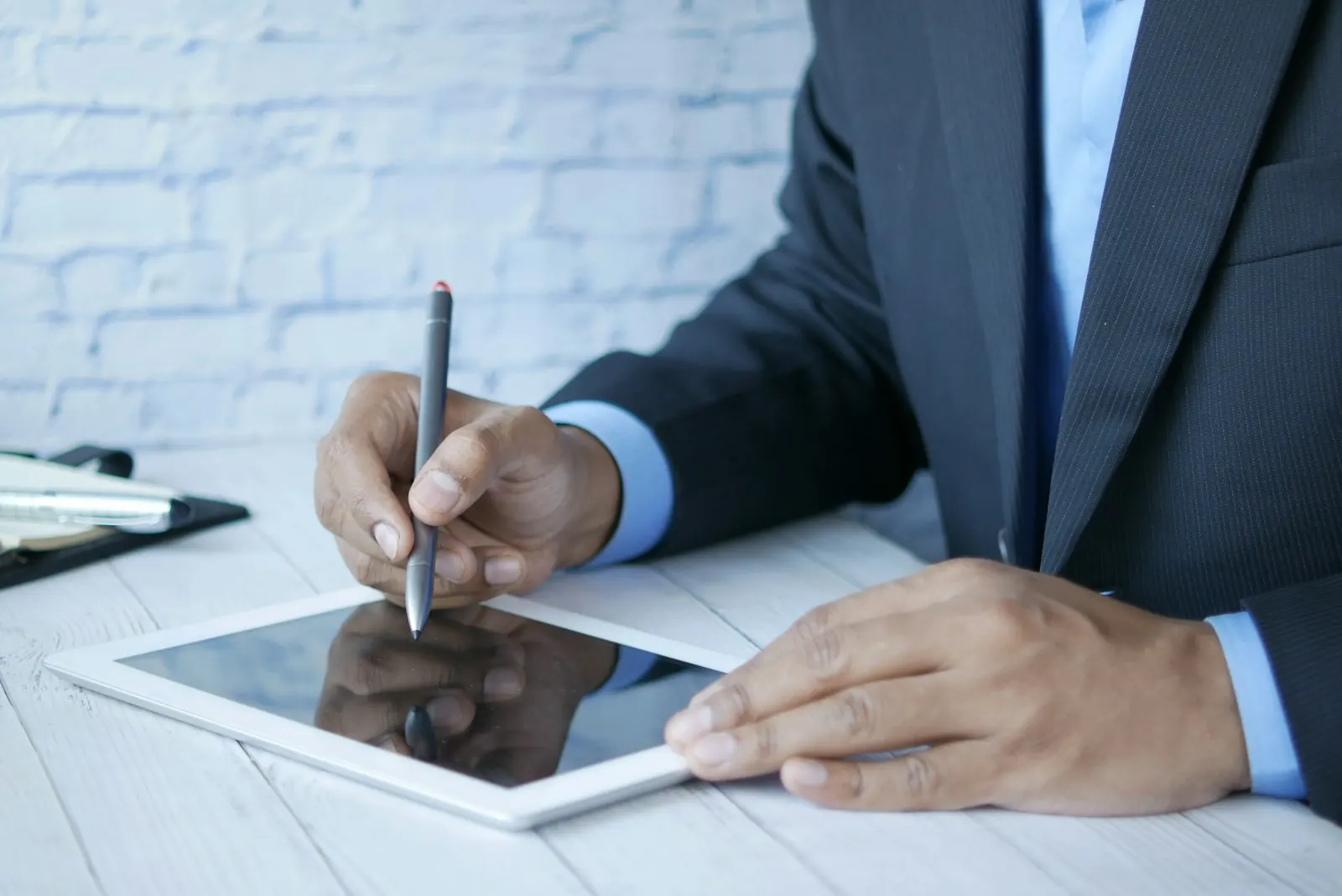 Une main signe sur une tablette avec un stylet