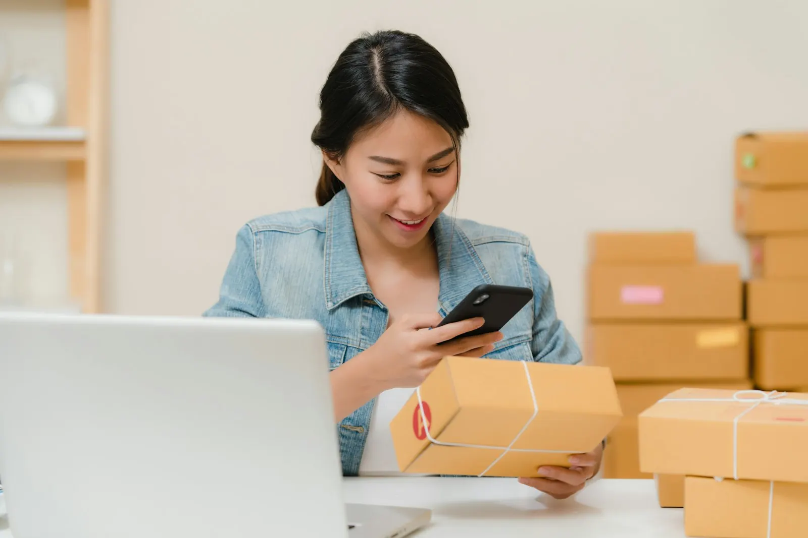 Une commerçante relit quelque chose sur son téléphone, devant son ordinateur